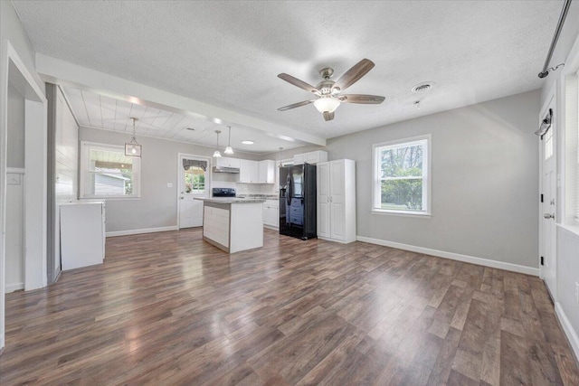1006 10th St, Glasgow, VA 24555 - kitchen with black refrigerator with ice dispenser, dark wood finished floors, a kitchen island, a textured ceiling, and white cabinetry