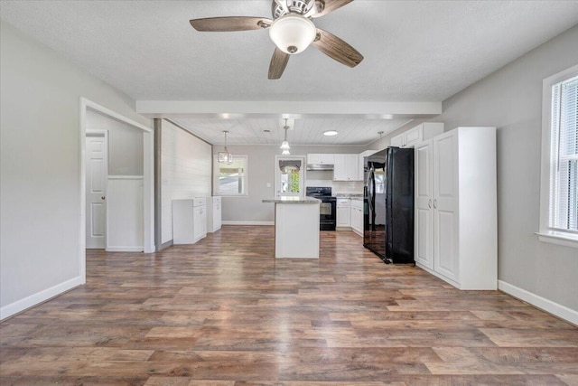 1006 10th St, Glasgow, VA 24555 - kitchen featuring black appliances, white cabinets, dark wood-type flooring, beamed ceiling, and a center island