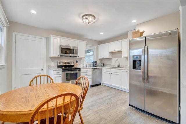 3023 Birchlawn Ave NW, Roanoke, VA 24012 - kitchen with stainless steel appliances, a sink, light countertops, white cabinets, and light wood finished floors