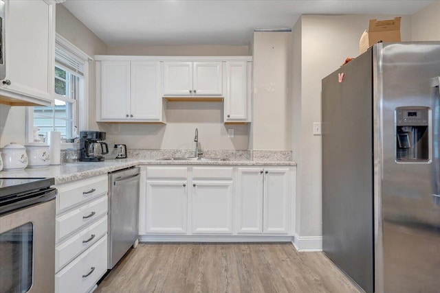 3023 Birchlawn Ave NW, Roanoke, VA 24012 - kitchen featuring stainless steel appliances, a sink, white cabinetry, light wood-type flooring, and light stone counters
