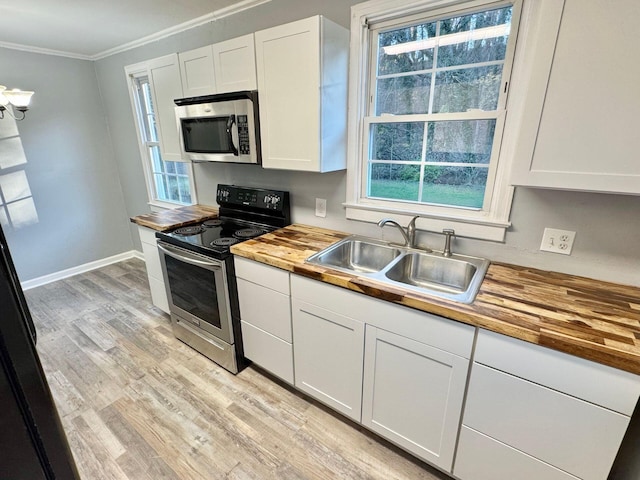 816 Brandon Ave SW, Roanoke, VA 24015 - kitchen with butcher block countertops, stainless steel appliances, a sink, ornamental molding, and light wood-type flooring