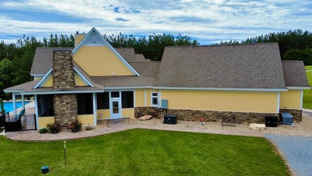 1038 Lees Mill Ln, Goode, VA 24556 - back of property with stone siding, a sunroom, a yard, central AC unit, and a chimney