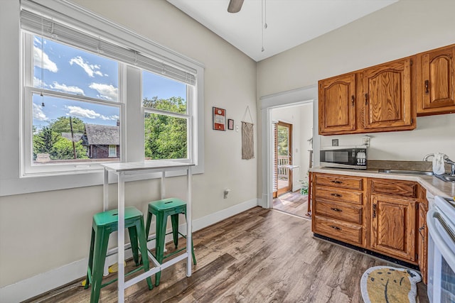602 Allison Ave SW, Roanoke, VA 24016 - kitchen with stainless steel microwave, a sink, electric stove, brown cabinets, and wood finished floors