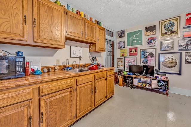 602 Allison Ave SW, Roanoke, VA 24016 - kitchen with a textured ceiling, light countertops, brown cabinets, and a sink