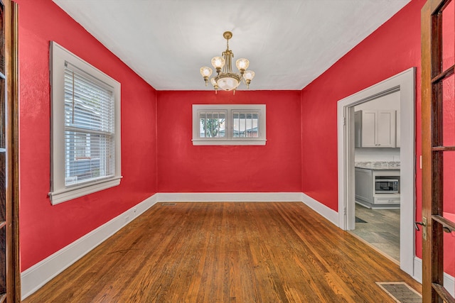1129 Howbert Ave SW, Roanoke, VA 24015 - empty room featuring wood finished floors, a chandelier, plenty of natural light, and baseboards