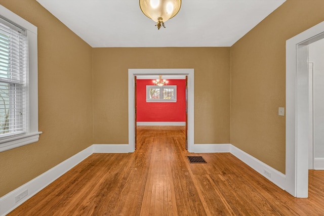 1129 Howbert Ave SW, Roanoke, VA 24015 - unfurnished room featuring a chandelier, wood finished floors, and baseboards