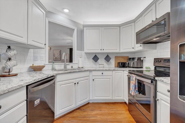 828 Ray St, Roanoke, VA 24019 - kitchen featuring stainless steel appliances, a sink, backsplash, light wood finished floors, and white cabinets