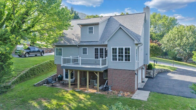828 Ray St, Roanoke, VA 24019 - rear view of house featuring a yard, brick siding, a deck, a chimney, and an attached garage