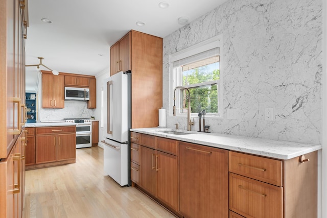 2561 Inglewood Rd SW, Roanoke, VA 24015 - kitchen featuring stainless steel appliances, a sink, backsplash, light wood-type flooring, and brown cabinetry