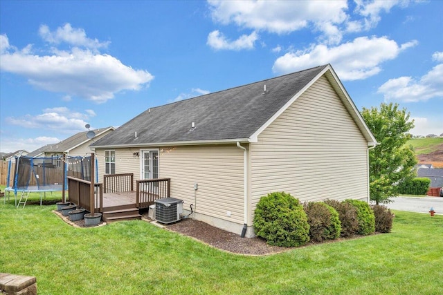 590 Keystone Dr NW, Christiansburg, VA 24073 - back of house featuring a wooden deck, a trampoline, a lawn, central AC unit, and a shingled roof