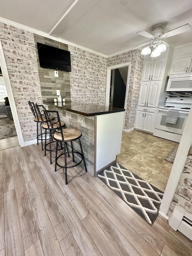 104 Wintergreen Ave, Clifton Forge, VA 24422 - kitchen with white appliances, white cabinetry, ornamental molding, a breakfast bar, and light wood-style flooring