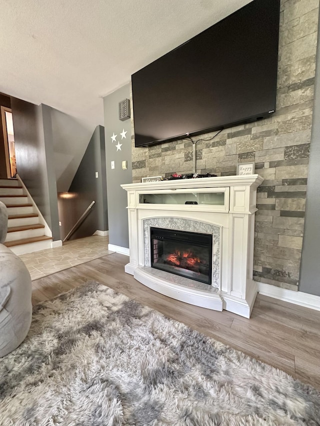 104 Wintergreen Ave, Clifton Forge, VA 24422 - living room featuring wood finished floors, baseboards, a premium fireplace, and a textured ceiling