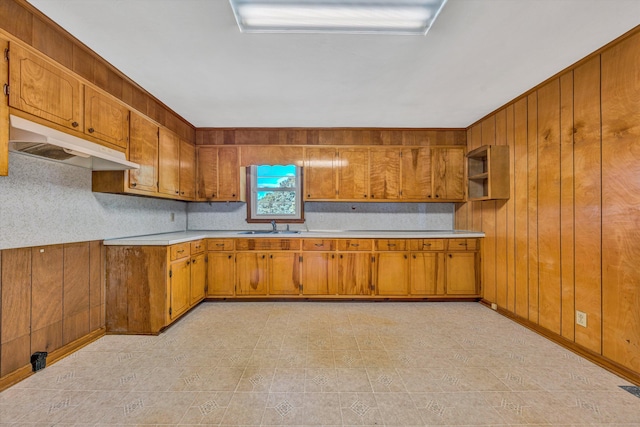 20083 Snow Creek Rd, Penhook, VA 24137 - kitchen with under cabinet range hood, brown cabinets, light countertops, a sink, and wood walls