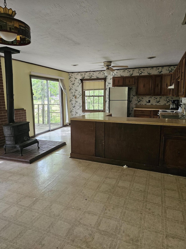 145 Carlos Rd, Union Hall, VA 24176 - kitchen with white appliances, light floors, wallpapered walls, a textured ceiling, and a wood stove
