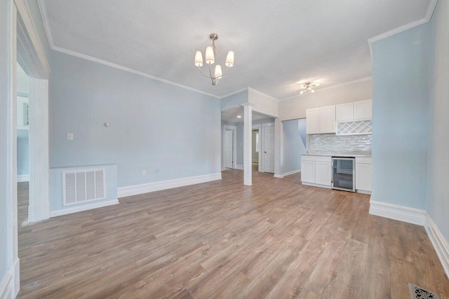 3311 Memorial Ave, Lynchburg, VA 24501 - unfurnished living room with beverage cooler, decorative columns, light wood-type flooring, a chandelier, and ornamental molding
