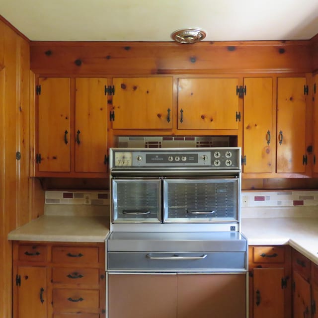 383 Main St, New Castle, VA 24127 - kitchen featuring oven, light countertops, backsplash, and brown cabinets
