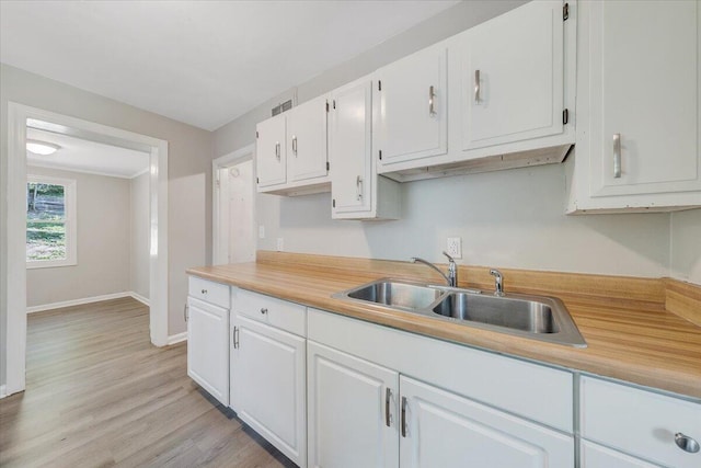 2109 Colgate St NE, Roanoke, VA 24012 - kitchen featuring a sink, white cabinets, light countertops, baseboards, and light wood-style flooring
