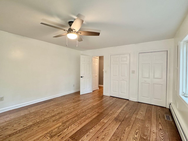 4867 Hunting Hills Dr, Roanoke, VA 24018 - unfurnished bedroom featuring baseboard heating, wood finished floors, baseboards, multiple closets, and a ceiling fan