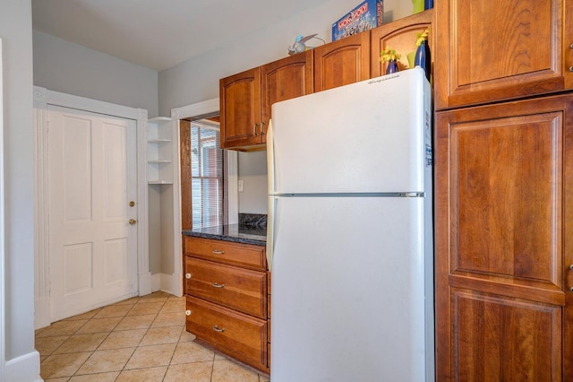 515 Elm Ave SW, Roanoke, VA 24016 - kitchen featuring freestanding refrigerator, light tile patterned floors, brown cabinets, and dark stone countertops