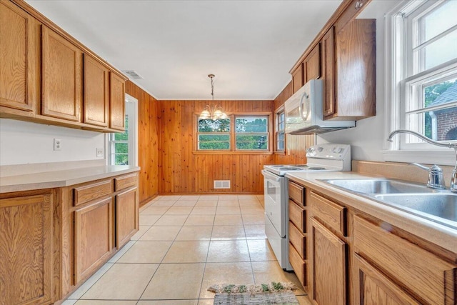 1113 Brandon Ave SW, Roanoke, VA 24015 - kitchen with white appliances, wood walls, brown cabinetry, and light countertops