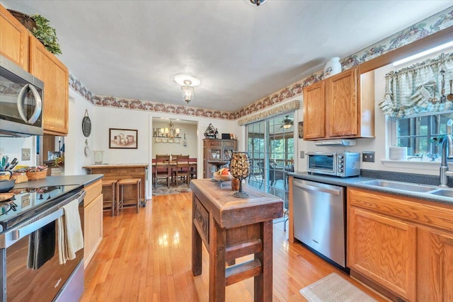 6119 Carolina Trl, Roanoke, VA 24019 - kitchen with stainless steel appliances, light wood-style floors, dark countertops, a sink, and a chandelier