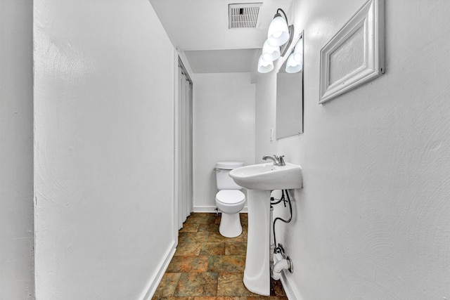 1002 Stewart Ave SE, Roanoke, VA 24013 - bathroom with stone finish flooring, toilet, baseboards, and a sink