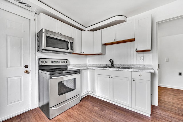 1002 Stewart Ave SE, Roanoke, VA 24013 - kitchen featuring stainless steel appliances, dark wood finished floors, a sink, white cabinetry, and baseboards