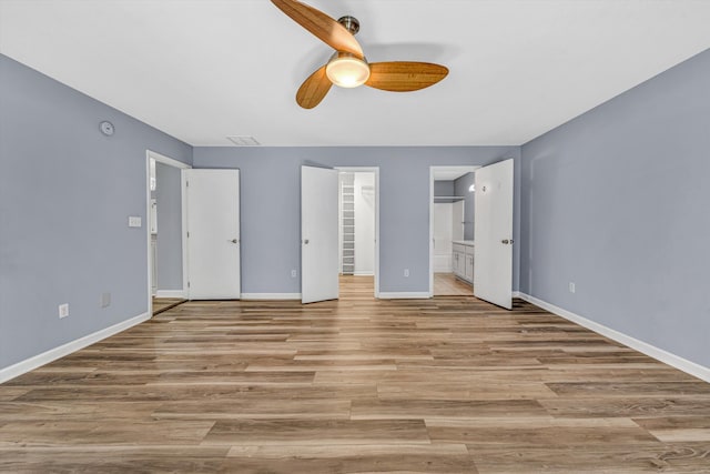 395 Middle Valley Rd, Hardy, VA 24101 - unfurnished bedroom with baseboards, connected bathroom, light wood finished floors, a ceiling fan, and a walk in closet
