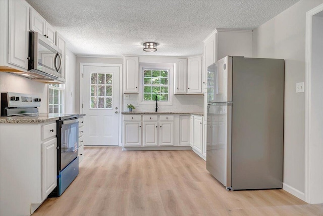 1632 Haymakertown Rd, Troutville, VA 24175 - kitchen featuring stainless steel appliances, light wood finished floors, a sink, white cabinetry, and a textured ceiling