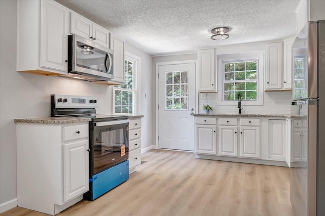 1632 Haymakertown Rd, Troutville, VA 24175 - kitchen featuring appliances with stainless steel finishes, white cabinets, light wood-style flooring, baseboards, and a textured ceiling