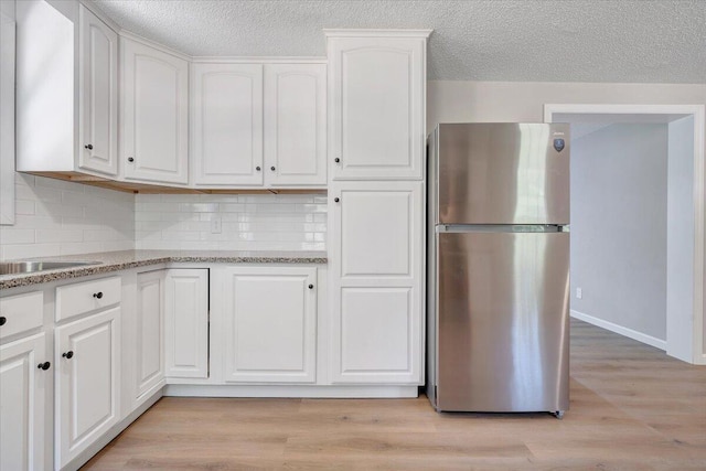 1632 Haymakertown Rd, Troutville, VA 24175 - kitchen with freestanding refrigerator, white cabinets, backsplash, light wood finished floors, and a textured ceiling