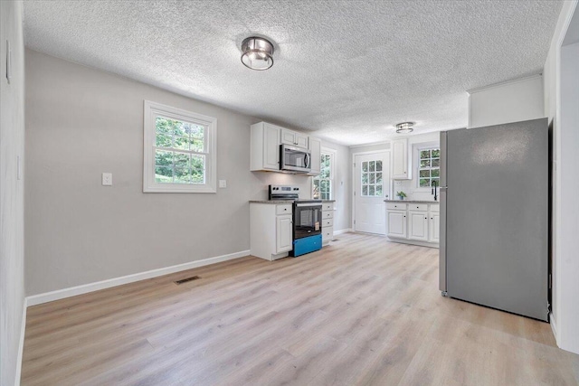 1632 Haymakertown Rd, Troutville, VA 24175 - kitchen with stainless steel appliances, white cabinetry, light wood-style flooring, baseboards, and a textured ceiling