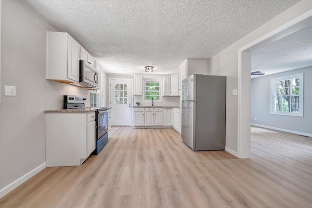 1632 Haymakertown Rd, Troutville, VA 24175 - kitchen featuring stainless steel appliances, a textured ceiling, light wood-style floors, white cabinetry, and a sink