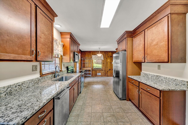 2527 Northminster Rd NW, Roanoke, VA 24012 - kitchen with stainless steel appliances, a sink, brown cabinets, light stone countertops, and decorative light fixtures
