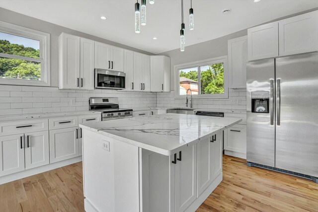 702 Commerce Ave, Iron Gate, VA 24448 - kitchen with stainless steel appliances, a center island, light wood-type flooring, backsplash, and white cabinets