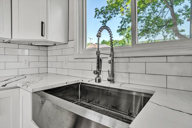 702 Commerce Ave, Iron Gate, VA 24448 - kitchen view of a sink, decorative backsplash, white cabinetry, and light stone countertops