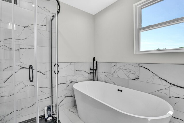 702 Commerce Ave, Iron Gate, VA 24448 - bathroom with tile walls, marble tiled flooring, a marble finish shower, a wainscoted wall, and a freestanding tub