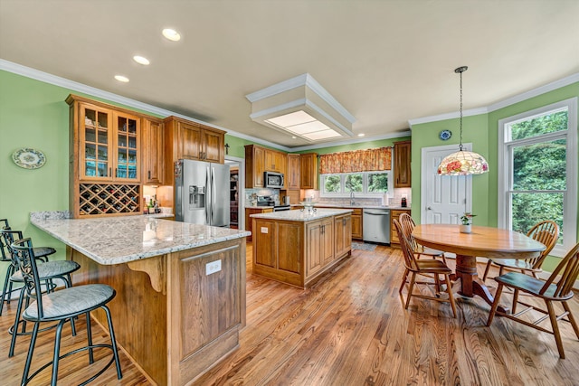 6355 Juliet Ct, Roanoke, VA 24018 - kitchen with stainless steel appliances, ornamental molding, light wood-type flooring, brown cabinetry, and a kitchen breakfast bar