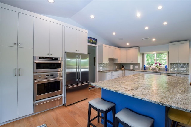 569 Sprinkle Rd, Fincastle, VA 24090 - kitchen with appliances with stainless steel finishes, a warming drawer, a kitchen breakfast bar, lofted ceiling, and tasteful backsplash