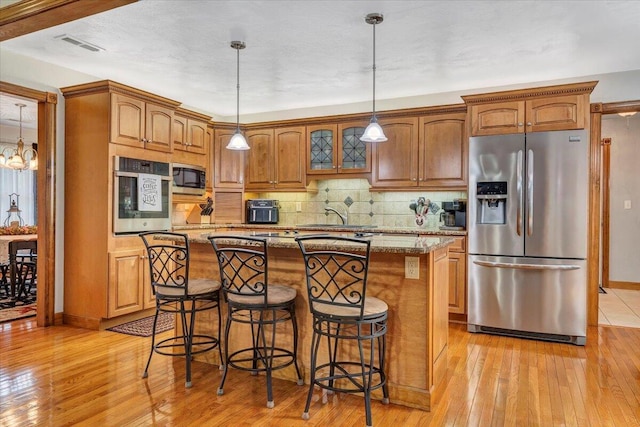 5335 Catawba Valley Dr, Catawba, VA 24070 - kitchen featuring appliances with stainless steel finishes, light wood-type flooring, decorative backsplash, a center island, and a breakfast bar