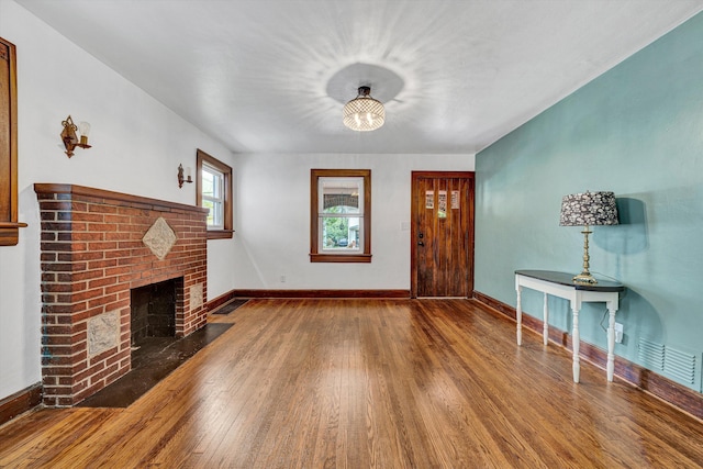 1618 8th St SE, Roanoke, VA 24013 - unfurnished living room featuring wood finished floors, a brick fireplace, and baseboards