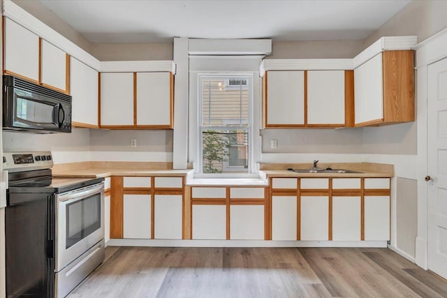 1523 Rorer Ave SW, Roanoke, VA 24016 - kitchen featuring black microwave, stainless steel range with electric stovetop, a sink, light countertops, and light wood-style flooring