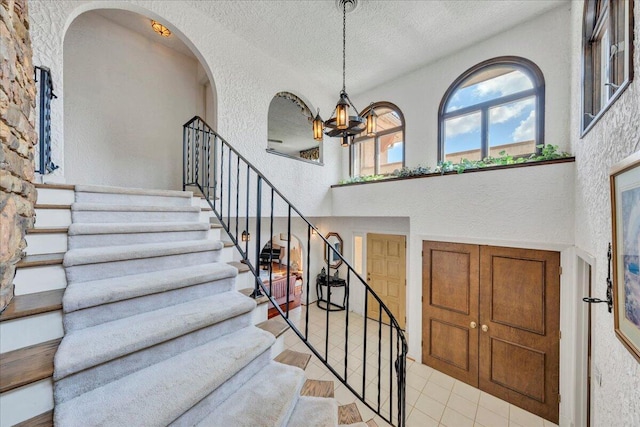 5880 Sugar Loaf Mountain Rd, Roanoke, VA 24018 - stairs with a textured wall, tile patterned flooring, a chandelier, a textured ceiling, and arched walkways