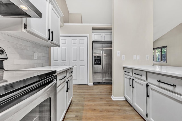 8757 Bent Mountain Rd, Roanoke, VA 24018 - kitchen featuring appliances with stainless steel finishes, range hood, light wood-type flooring, backsplash, and light countertops