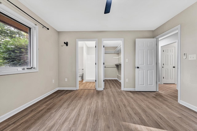 8757 Bent Mountain Rd, Roanoke, VA 24018 - unfurnished bedroom featuring wood finished floors, a walk in closet, a closet, and a ceiling fan