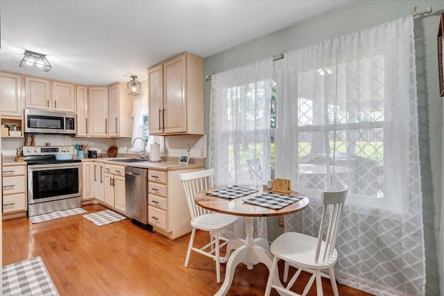 245 Queen Regent Ct, Blue Ridge, VA 24064 - kitchen with stainless steel appliances, light countertops, light wood-style floors, light brown cabinetry, and decorative backsplash