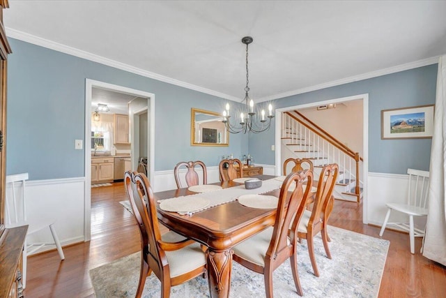 245 Queen Regent Ct, Blue Ridge, VA 24064 - dining area with stairway, a chandelier, light wood finished floors, crown molding, and a wainscoted wall
