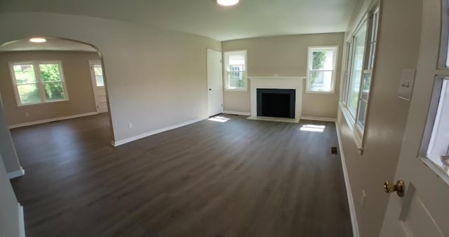 214 E Madison St, Covington, VA 24426 - unfurnished living room featuring dark wood-type flooring, plenty of natural light, arched walkways, a fireplace with flush hearth, and recessed lighting