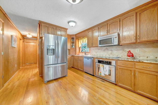 3203 Bradshaw Rd, Salem, VA 24153 - kitchen with appliances with stainless steel finishes, light wood finished floors, tasteful backsplash, a textured ceiling, and light stone counters
