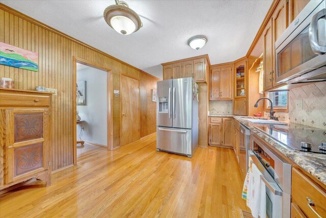 3203 Bradshaw Rd, Salem, VA 24153 - kitchen featuring stainless steel appliances, tasteful backsplash, light wood-style floors, glass insert cabinets, and wooden walls